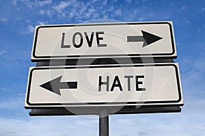 White two street signs with arrow on metal pole with word love and hate