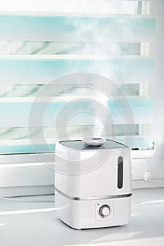 The white ultrasonic humidifier on a window moistens dry air