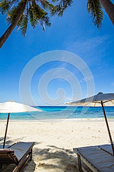 White umbrella and chairs on white beach