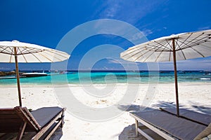 White umbrella and chairs on white beach