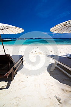 White umbrella and chairs on white beach