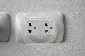 White universal electricity sockets plug on a white wall.