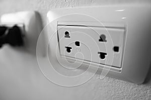 White universal electricity sockets plug on a white wall.