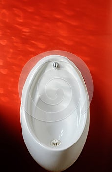 White Urinal Basin Against Red Wall