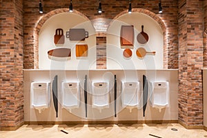 White urinal with rows of automatic pouring sensors and barriers in a modern supermarket and brick