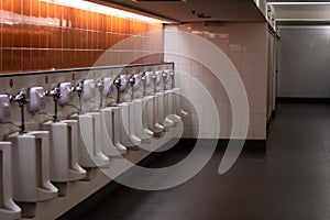 White urinal on wall in public men`s toilet with low light