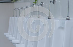 White urinals in men public toilet. Ceramic urinals in a row in men restroom. Man bladder health with urinary incontinence problem
