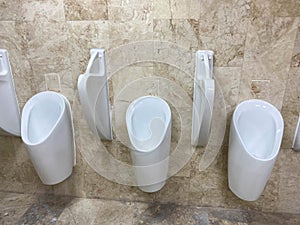 White urinals in men`s bathroom, public toilet