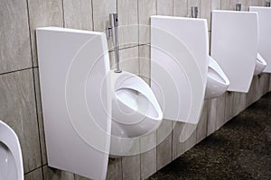 White urinals in the men`s room. Cleanliness hygiene of public toilets