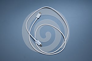 White USB cable for charging and data transfer coiled on blue background