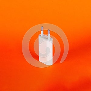 White USB euro plug wall charger adapter for mobile phone on orange background