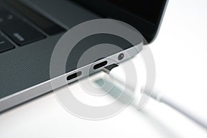 A white USB type C / USB-C cable being plugged into a modern notebook / laptop computer