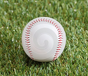 A white used baseball on the fresh green grass