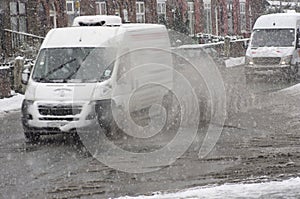 White van rides on big puddle in snowy day.