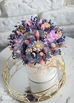 White vase with lavander on mirror and stoun wall background. Colorful summer bouquet of purple lavender and dried flowers