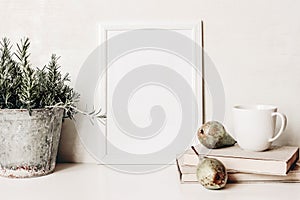 White vertical blank wooden frame mockup. Composition of rosemary herb in old metal flower pot, books, cup of coffee and