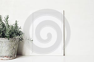 White vertical blank wooden frame mockup with rosemary herb in old metal flower pot on the table. Rustic summer poster