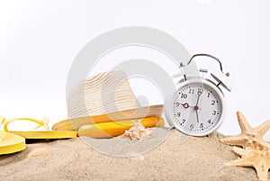 White vintage alarm clock with beach items on the sand