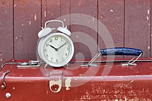 White vintage alarm clock and brown retro suitcase closeup. Time running out concept