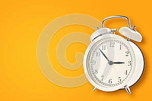 White vintage alarm clock on a yellow background. Urgency, deadline and running out of time concept