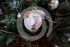 White vintage ball with fabric bow hanging on Christmas tree across other decorations close-up. Christmas decoration on a tree. Ho