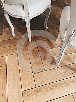 White vintage chairs with soft textile seats on a wooden floor background