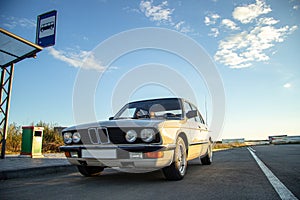 White vintage classic car with round headlights with the blue sky in the background