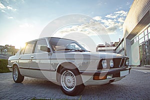 White vintage classic car with round headlights with the blue sky in the background