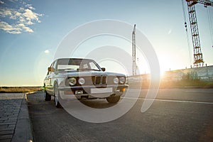 White vintage classic car with round headlights on the road during sunset