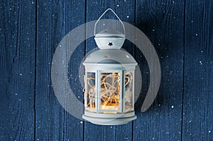 White vintage Lantern with burning candles, pine cones on wooden table and glitter lights background. Christmas background. happy