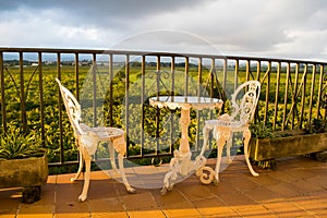 White vintage wrought iron gardening furniture, set of empty round table and two elegant chairs on the balcony