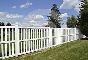 White vinyl fence by green lawn