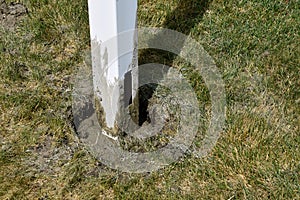 White vinyl post for a privacy fence cemented in pre-dug h hole.