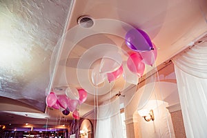 White, violet and pink balloons hang under the ceiling