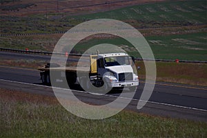 White Volvo Semi-Truck / Empty Flatbed Trailer