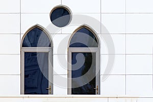 White wall with an arched and round windows, detail of building exterior