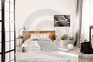 White wall with black map in modern bedroom with king size bed with wooden headboard