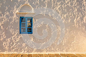 White wall with blue window at sunset