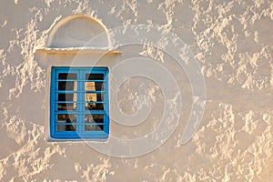 White wall with blue window at sunset