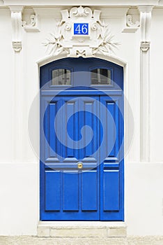 White wall of the house with a closed blue wooden door in Paris, France