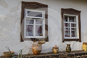 White wall of old clay house with two windows with wooden frame