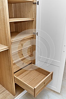 White wardrobe with wooden drawers and shelves. Wooden filling of wardrobe