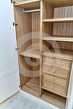 White wardrobe with wooden drawers and shelves. Wooden filling of wardrobe