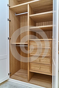 White wardrobe with wooden drawers and shelves. Wooden filling of wardrobe