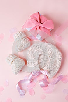 White warm handknitted baby shoes and bonnet for little girl or boy and gift box - concept of first step, birthday party, baby