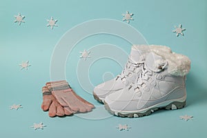 White warm sneakers and knitted gloves on a blue background with snowflakes