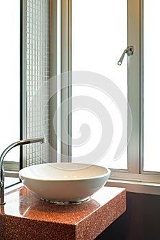 White wash basin with steel faucet in empty bathroom