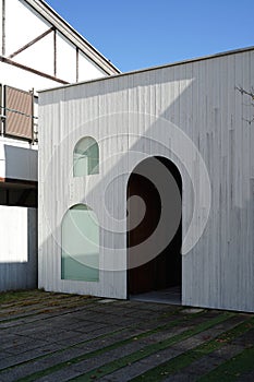 White washes timber plank facade of the building with arch door and windows