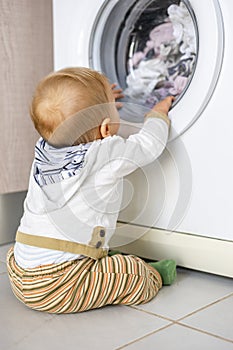 White washing machine keeps busy the little baby boy