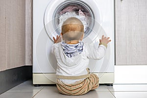 White washing machine keeps busy the little baby boy